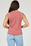 Person wearing a pink sleeveless top and light blue jeans on a plain background